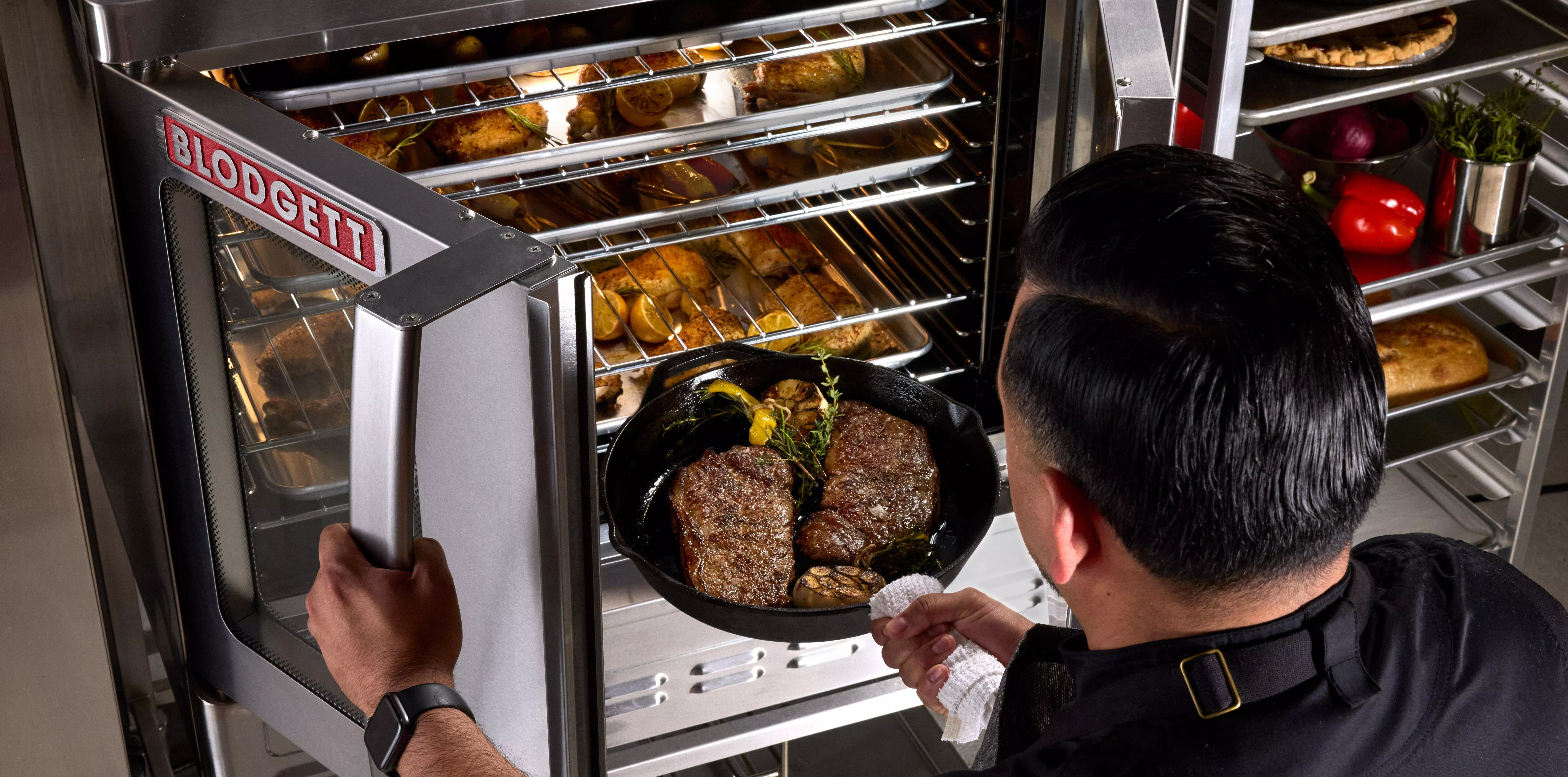 Chef placing a skillet of steaks into a Blodgett commercial oven.