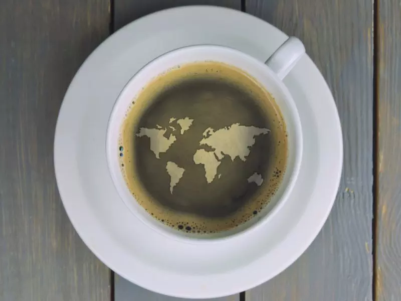 Cup of coffee with world map design on the surface.