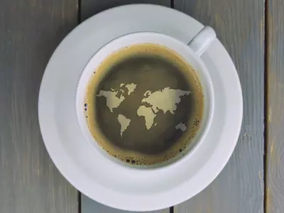 Cup of coffee with world map design on the surface.