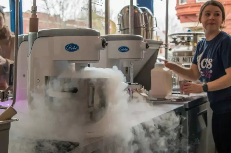 Machines labeled "Globe" emitting vapor, with a person pouring liquid from a jug.