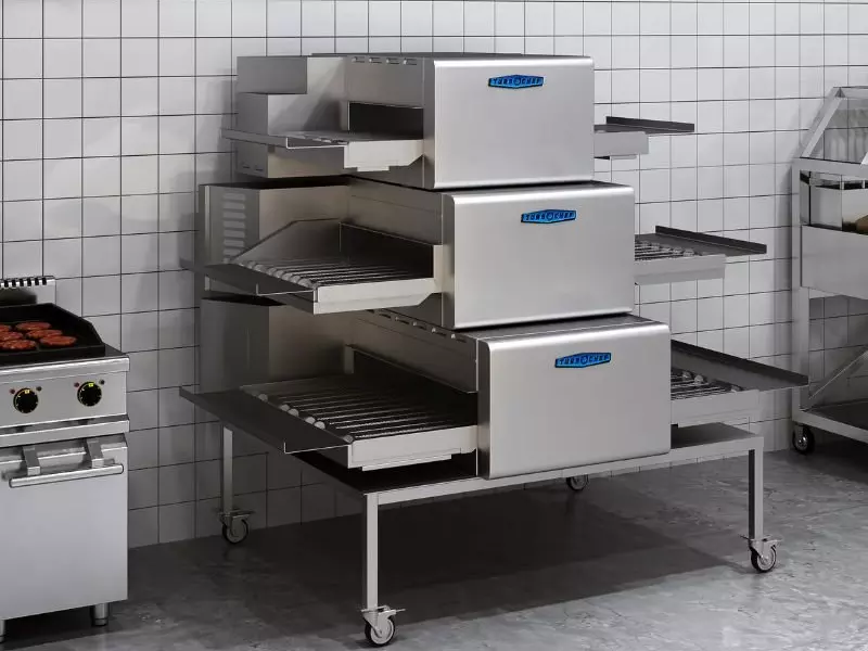 Triple-tier stainless steel conveyor oven with TurboChef branding in a tiled kitchen.