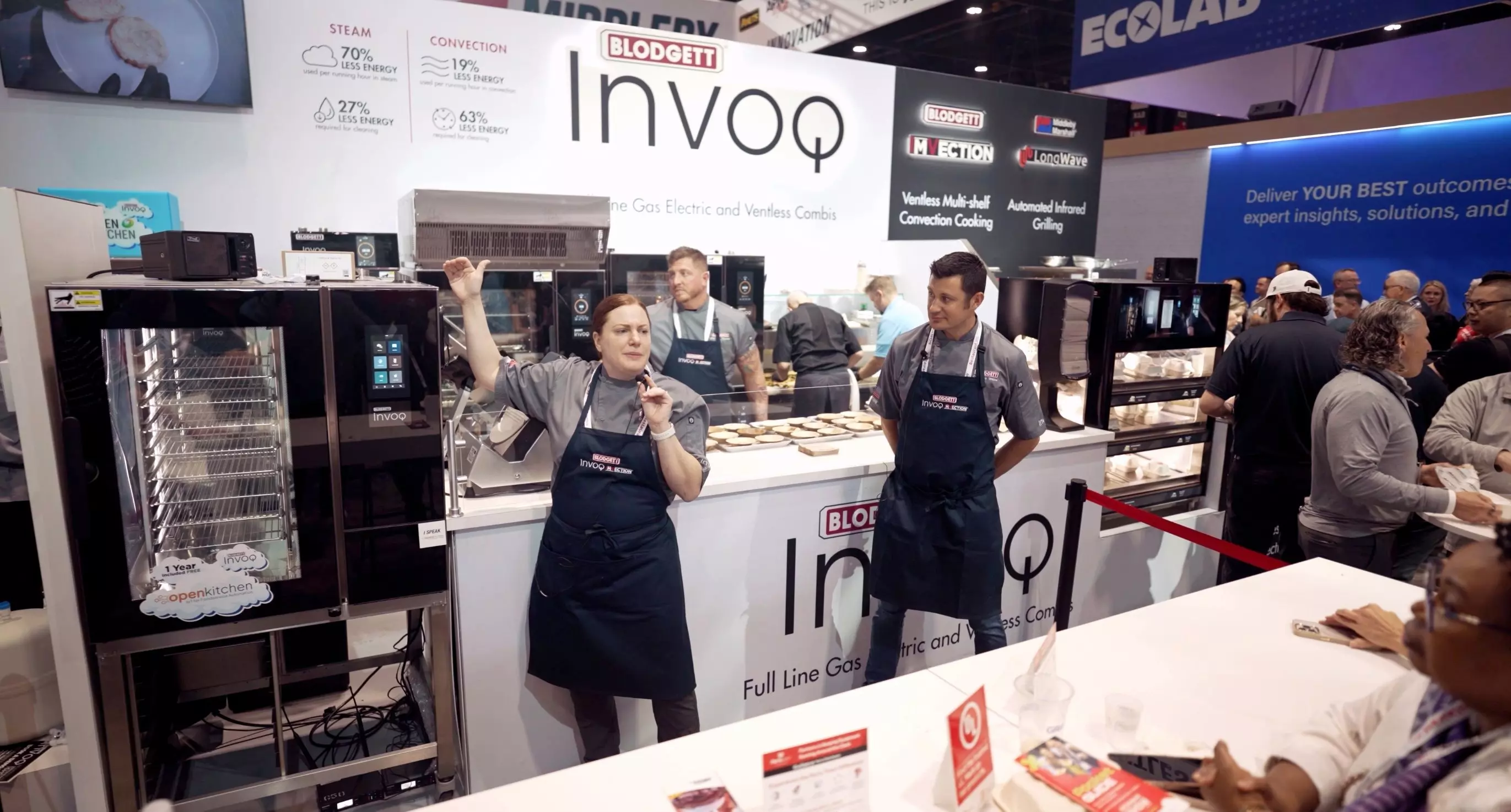Blodgett Invoq oven demo at a trade show, with chefs presenting and attendees watching.