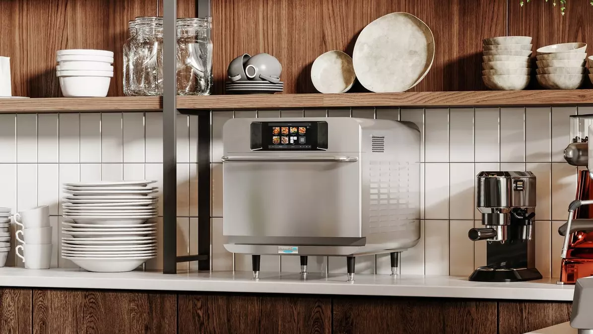 Countertop commercial oven with touchscreen beside an espresso machine and stacked dishes.