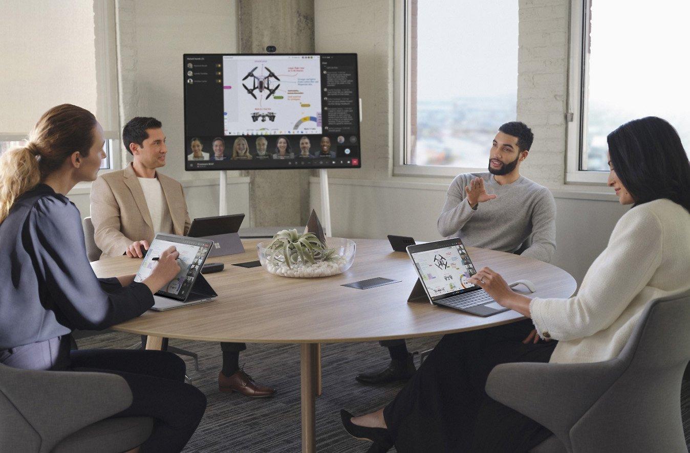 a group of people sitting around a table with laptops