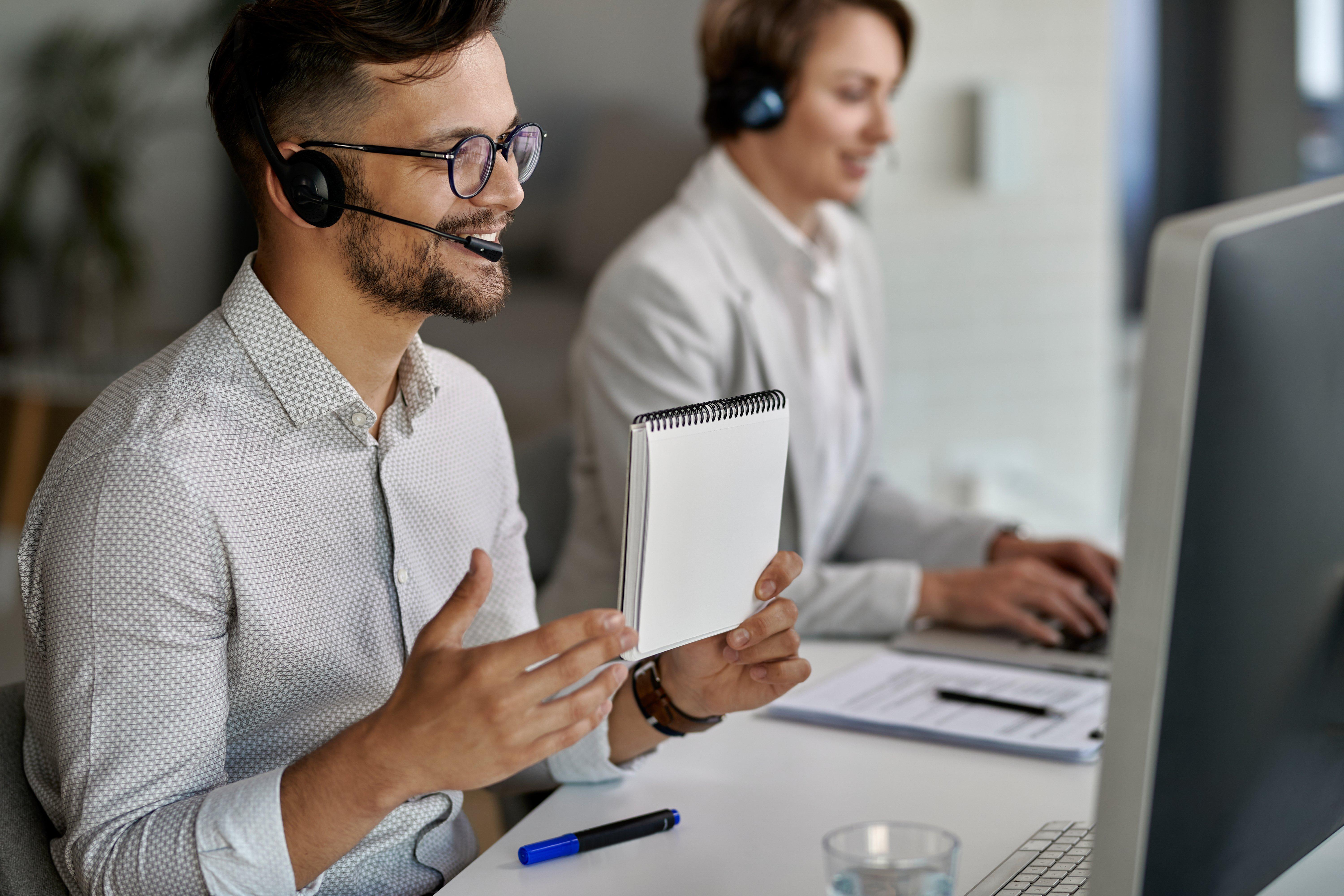 two people in headsets working at a computer