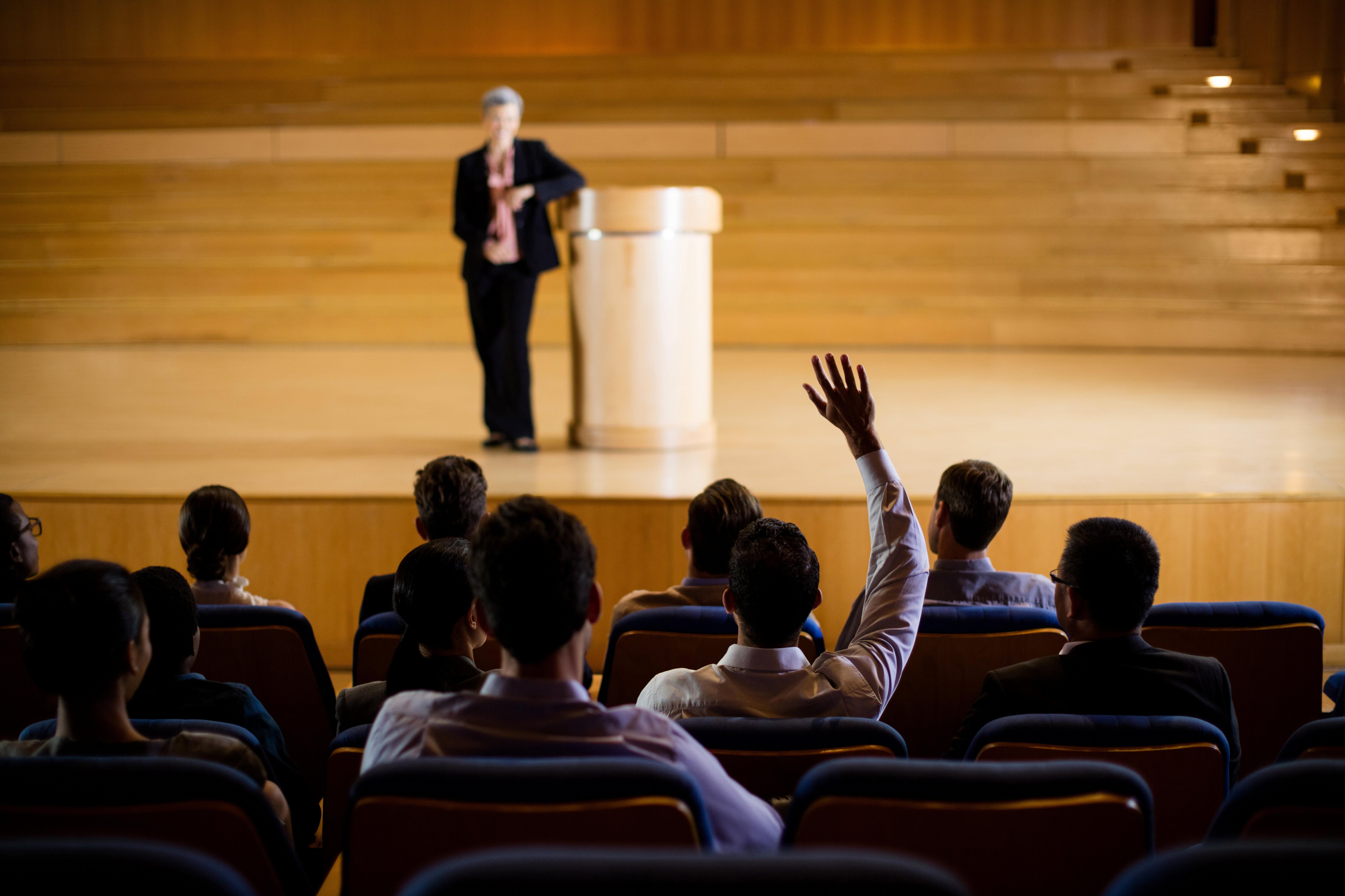 a man giving a speech to a crowd of people in a auditorium