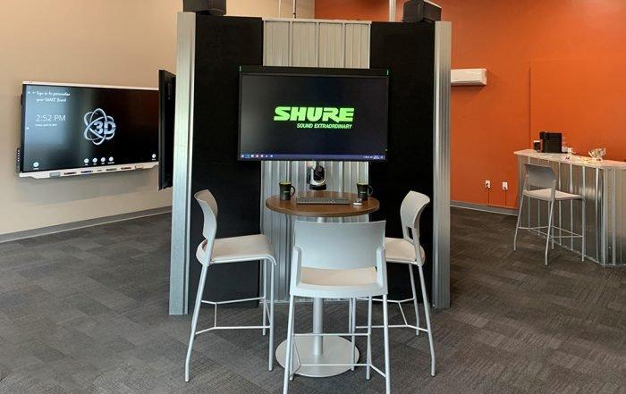 une pièce avec un grand écran et une table avec des chaises