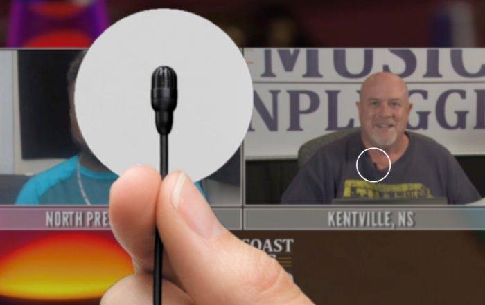 Deux hommes sont assis devant un microphone, dont l’un porte une chemise bleue.