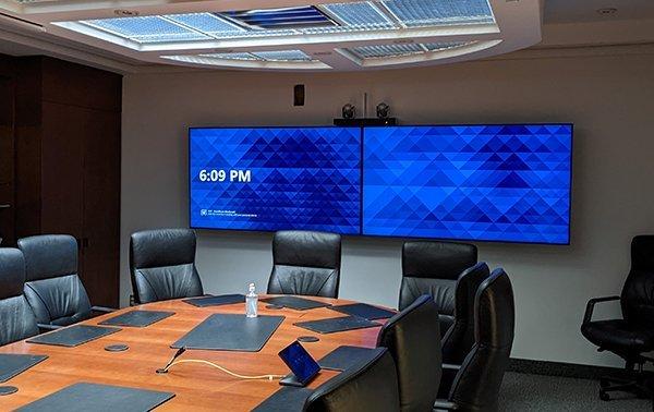 une salle de conférence avec une grande table, des chaises et un grand téléviseur à écran plat