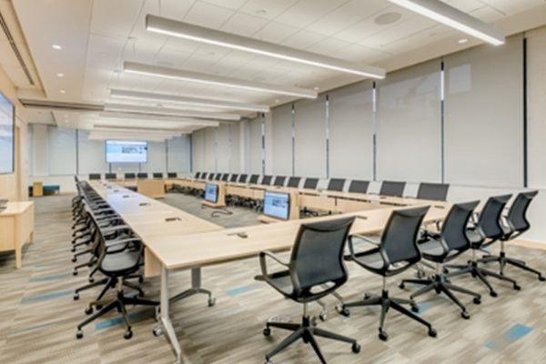 vue partagée d’une salle de conférence avec une grande table, des chaises et un grand téléviseur à écran plat