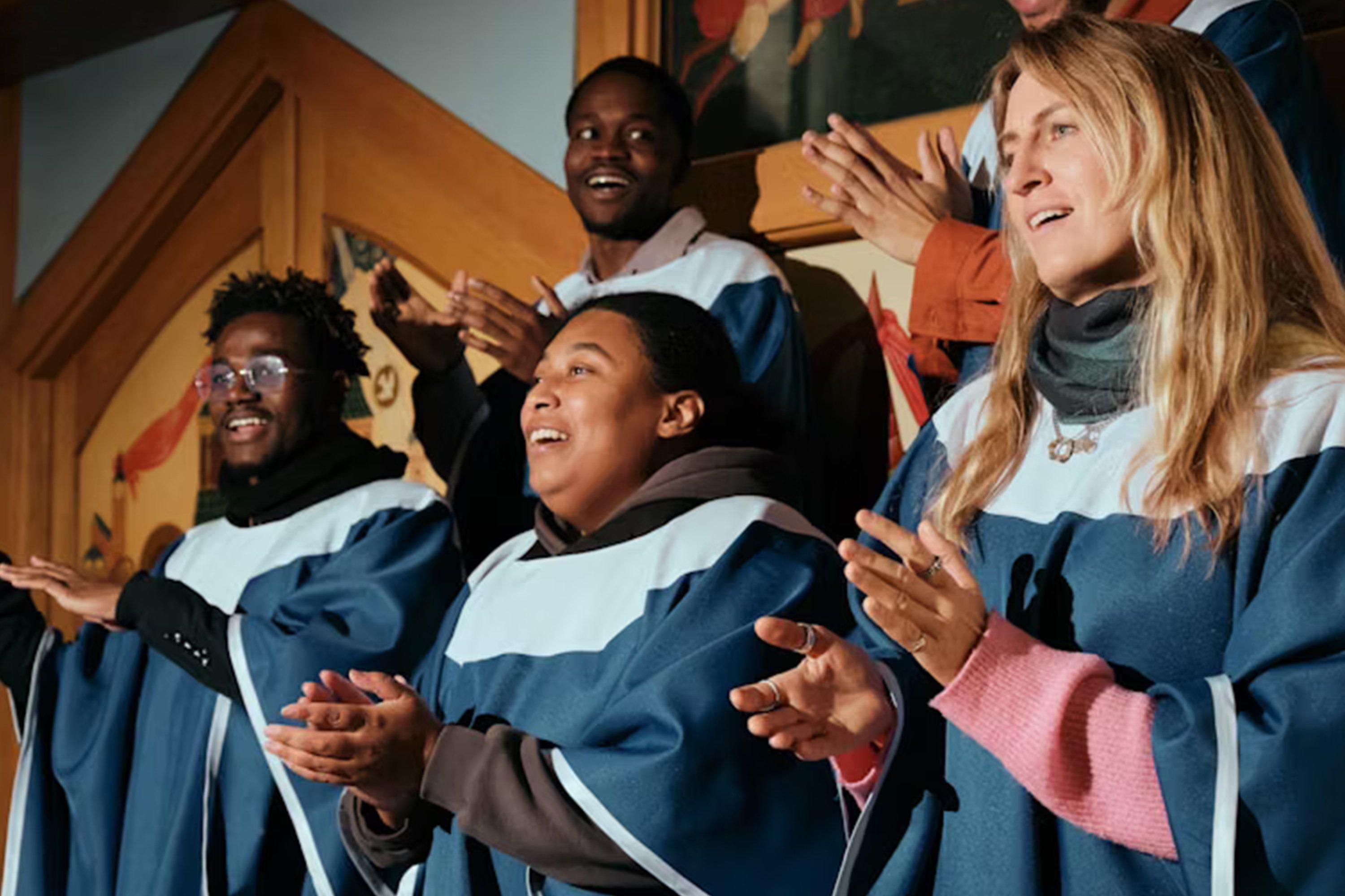 a group of people in blue robes clapping and smiling
