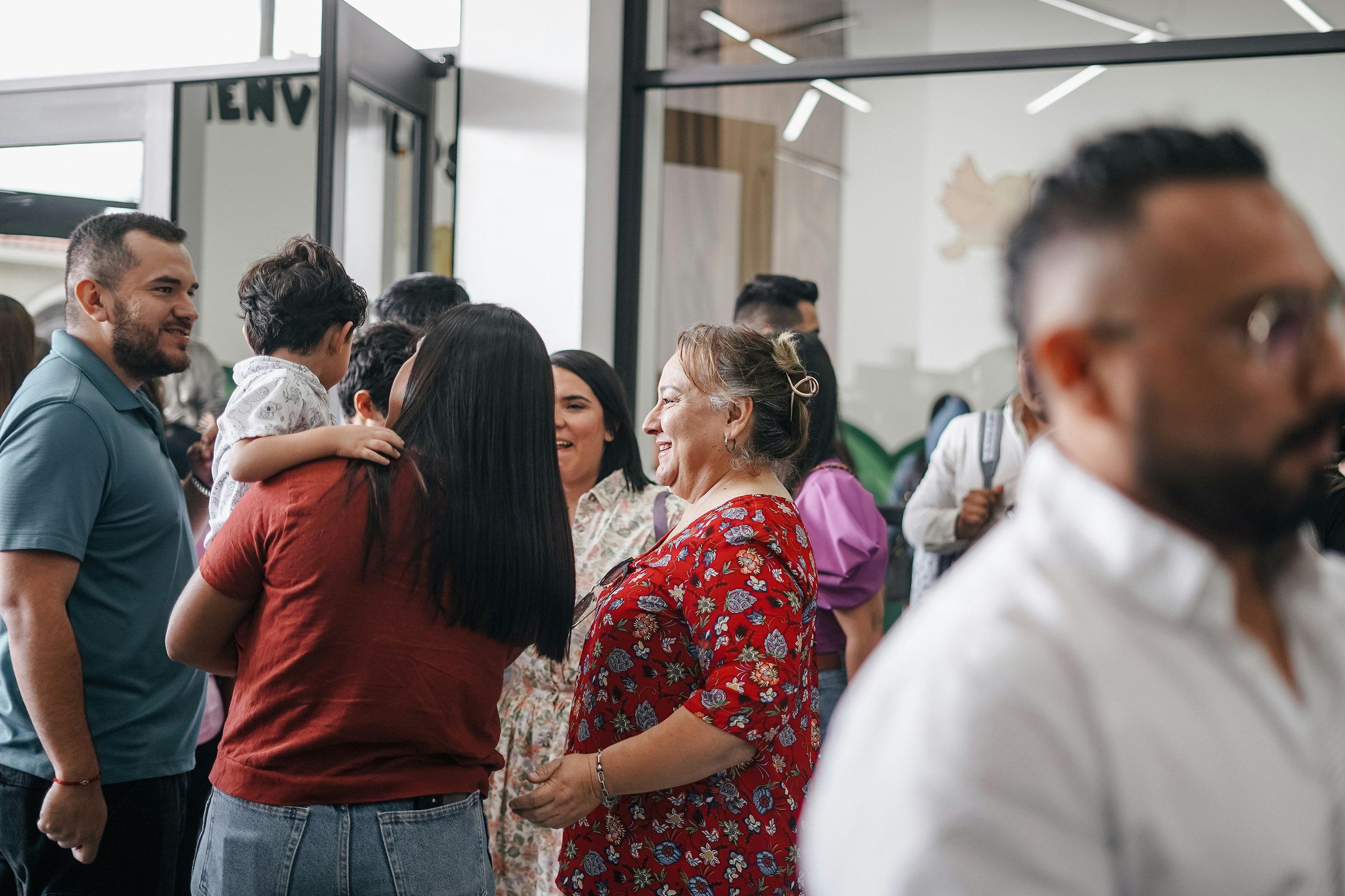 a group of people standing in a room with a woman holding a child