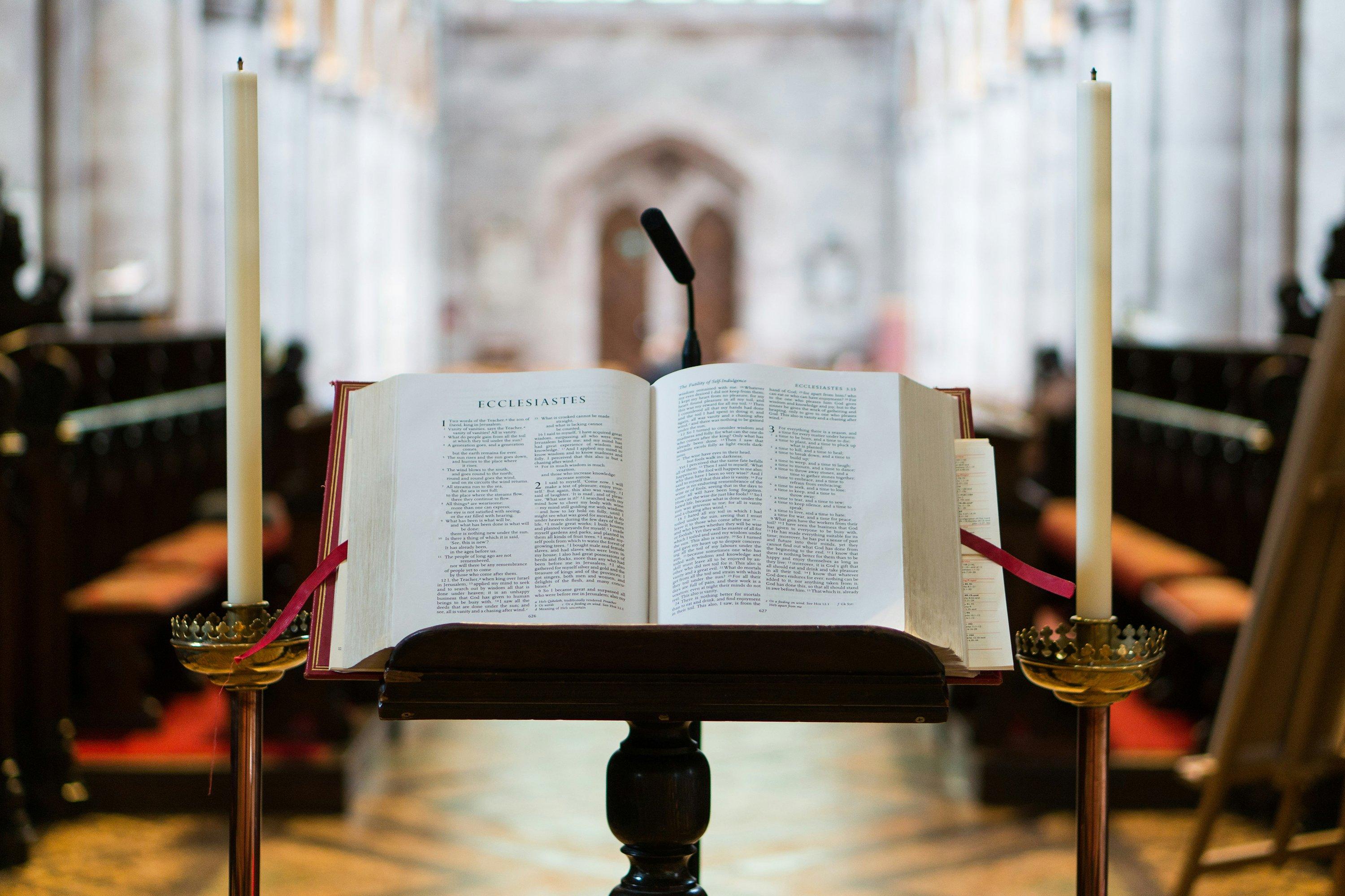 a bible on a stand in a church with two candles