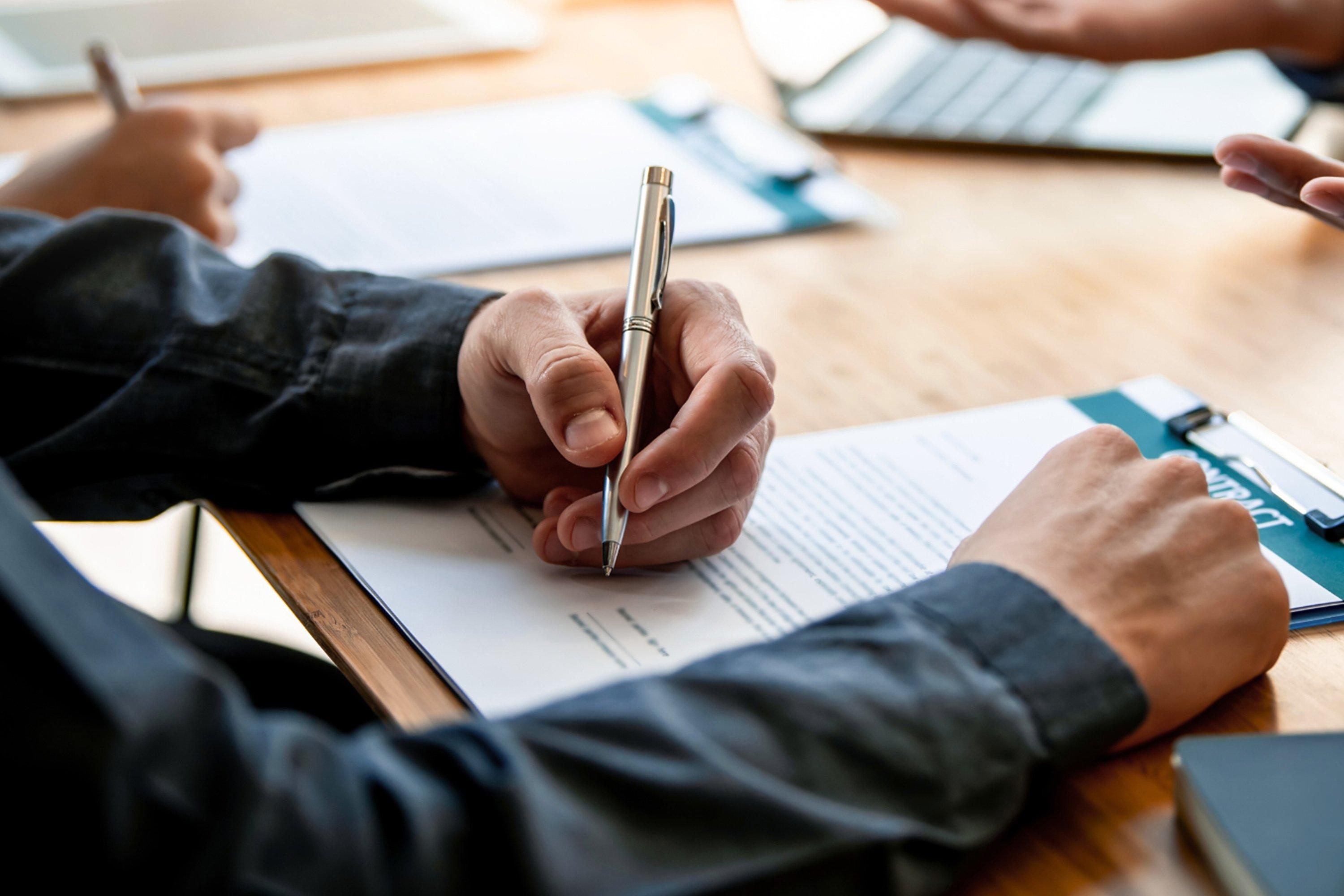 a person writing on a piece of paper with a pen
