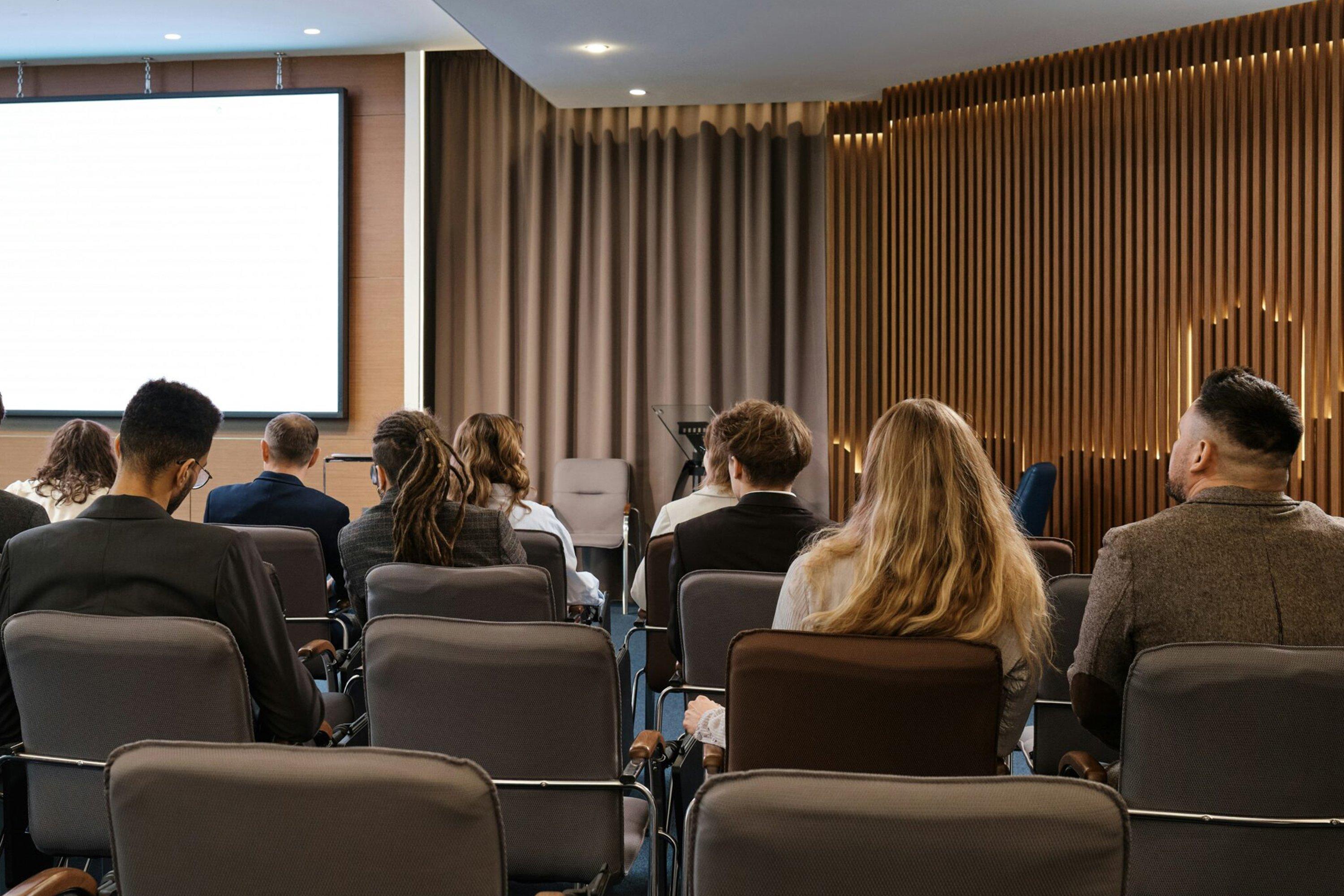 a group of people sitting in chairs watching a presentation on a screen