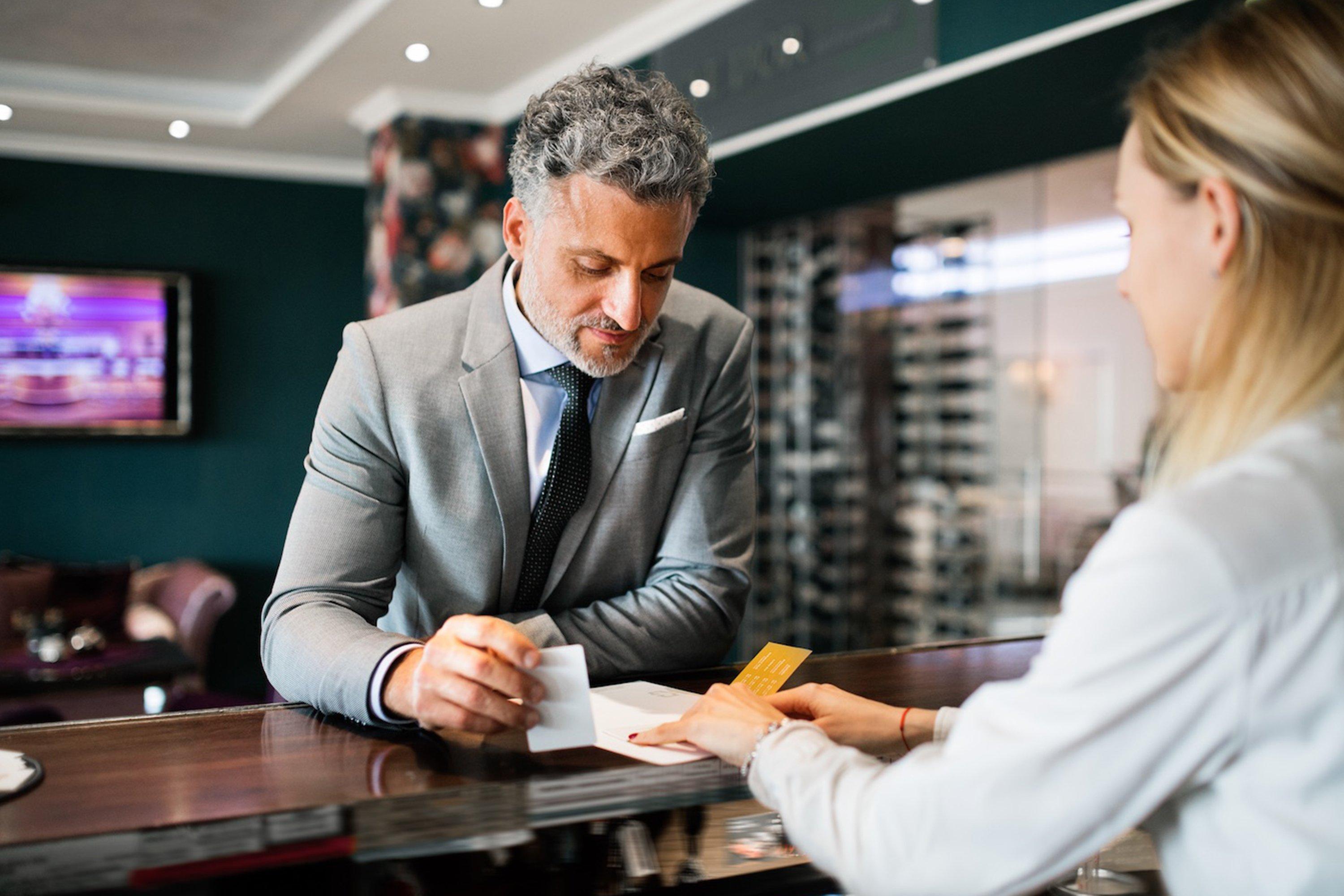 a man and woman sitting at a bar with a man writing something on a piece of paper