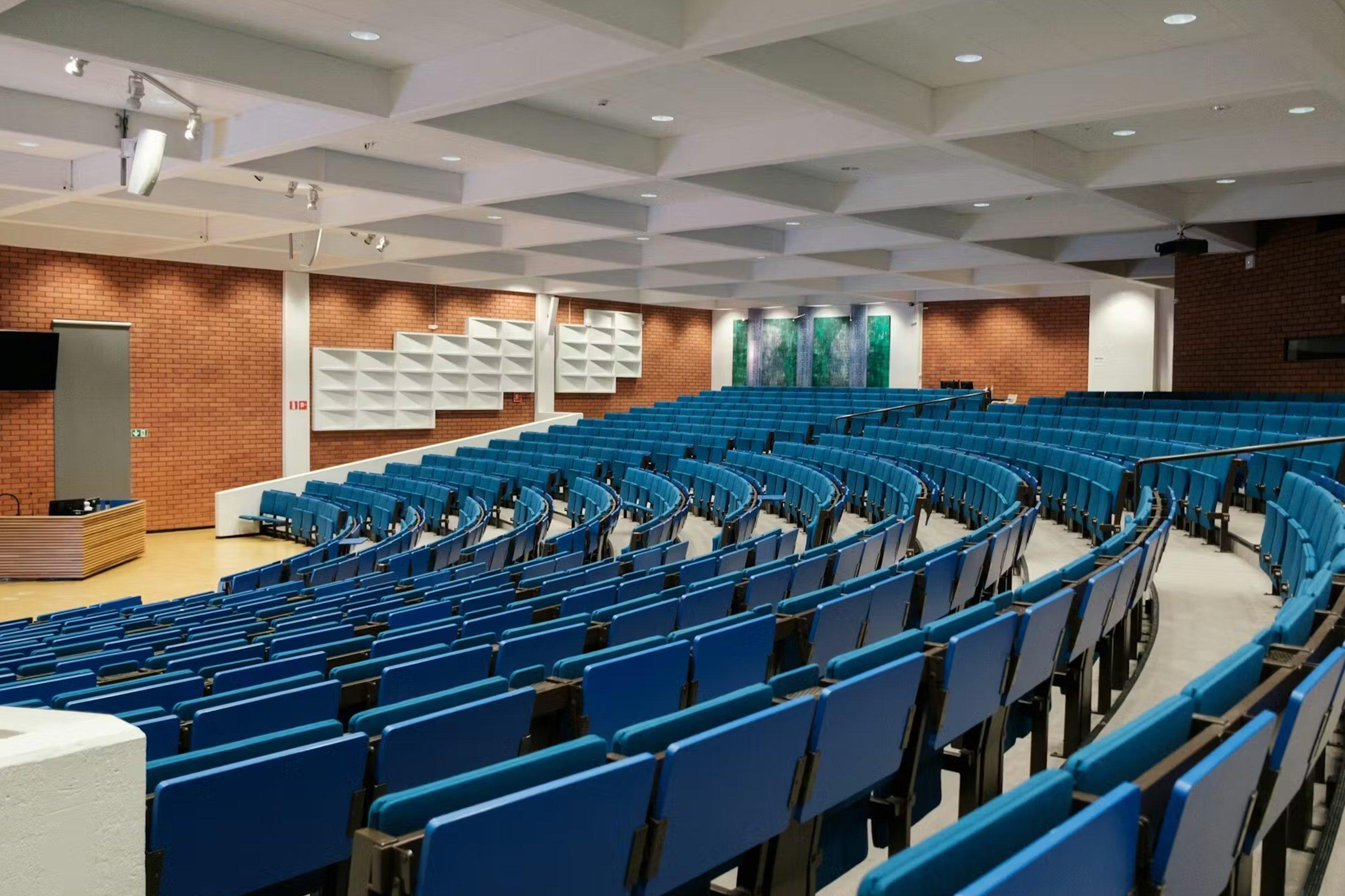 un grand auditorium avec des rangées de chaises bleues et une scène