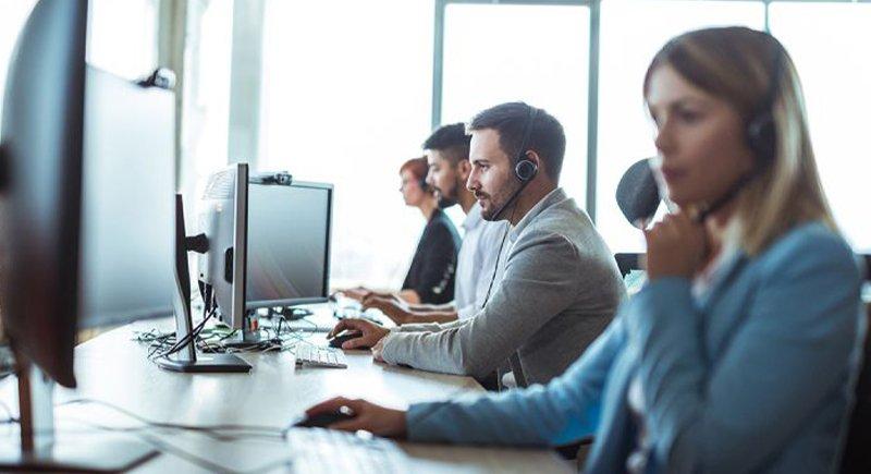 a group of people sitting at a desk with headsets on