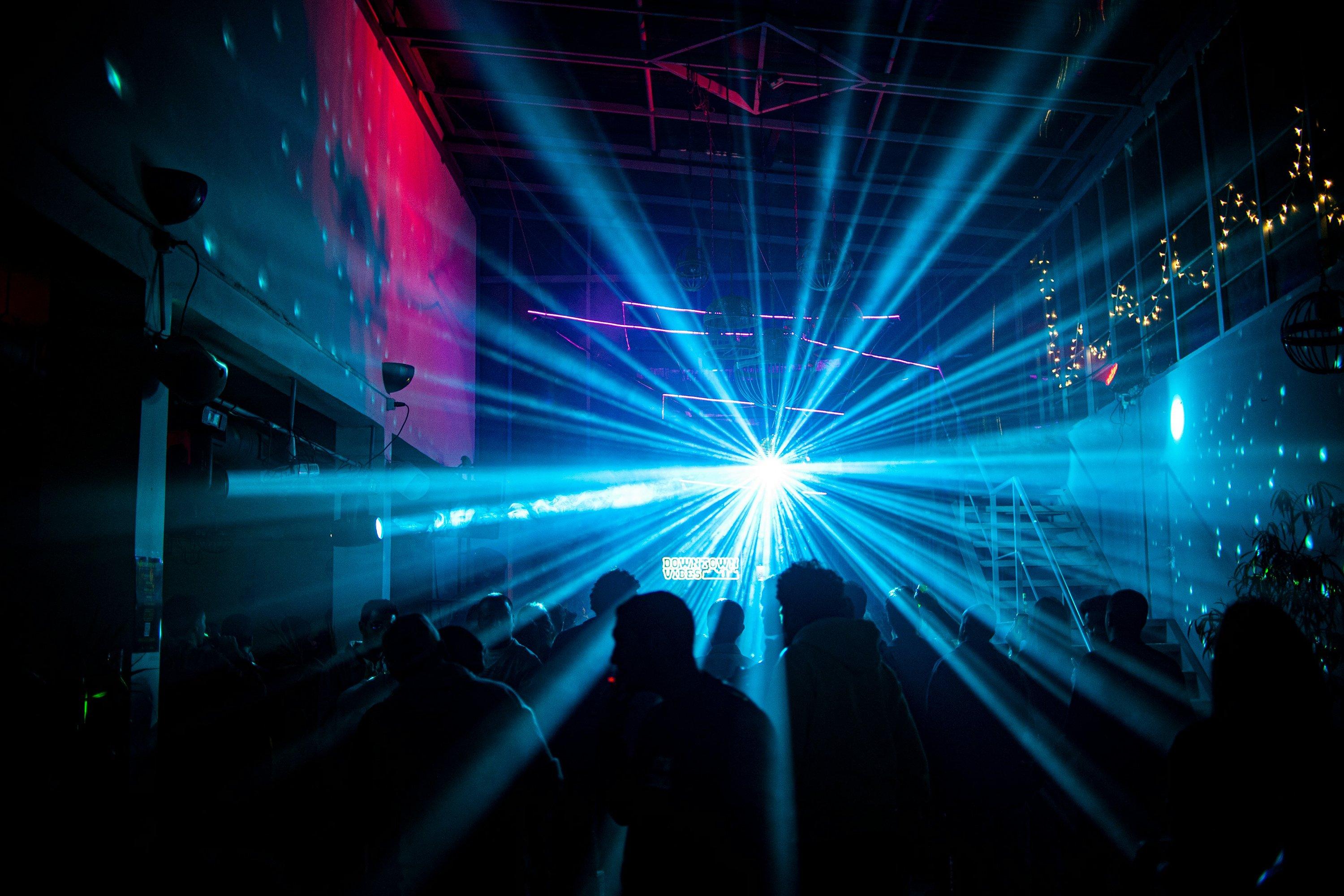 a group of people standing in a dark room with bright lights