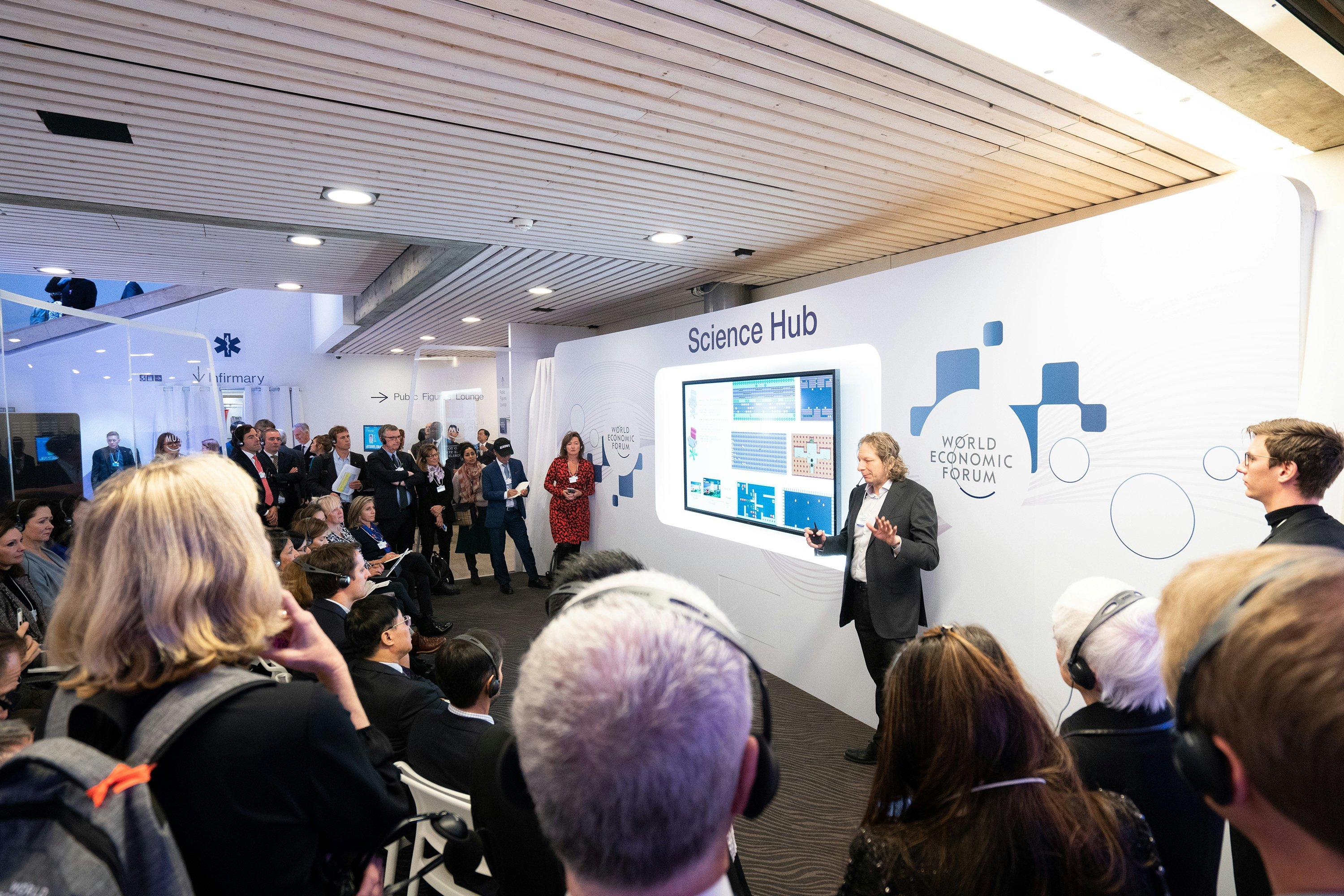 a group of people are gathered in a room listening to a speaker