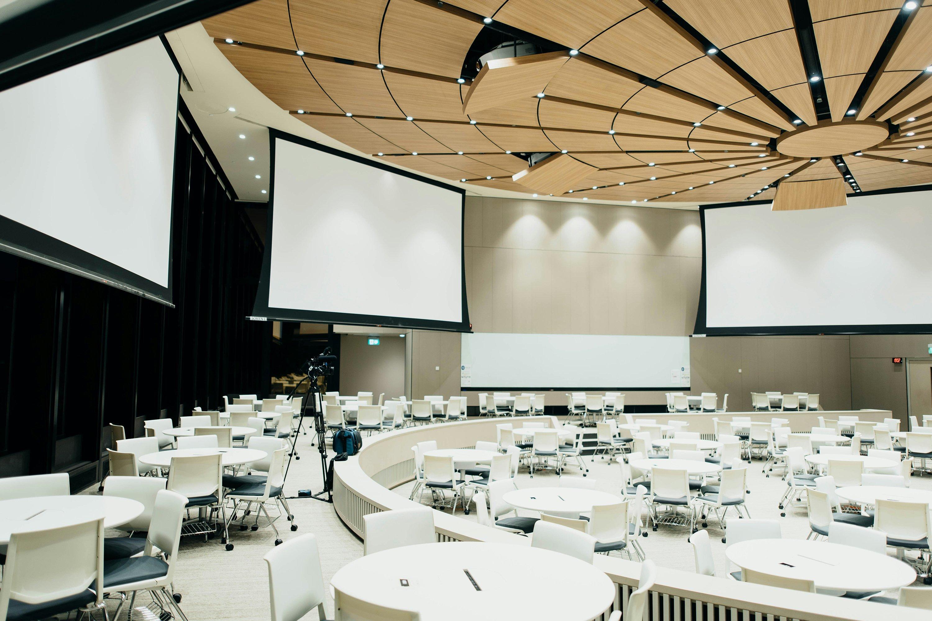 a large room with a large screen and a lot of tables