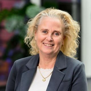 a woman with curly blonde hair smiling at the camera