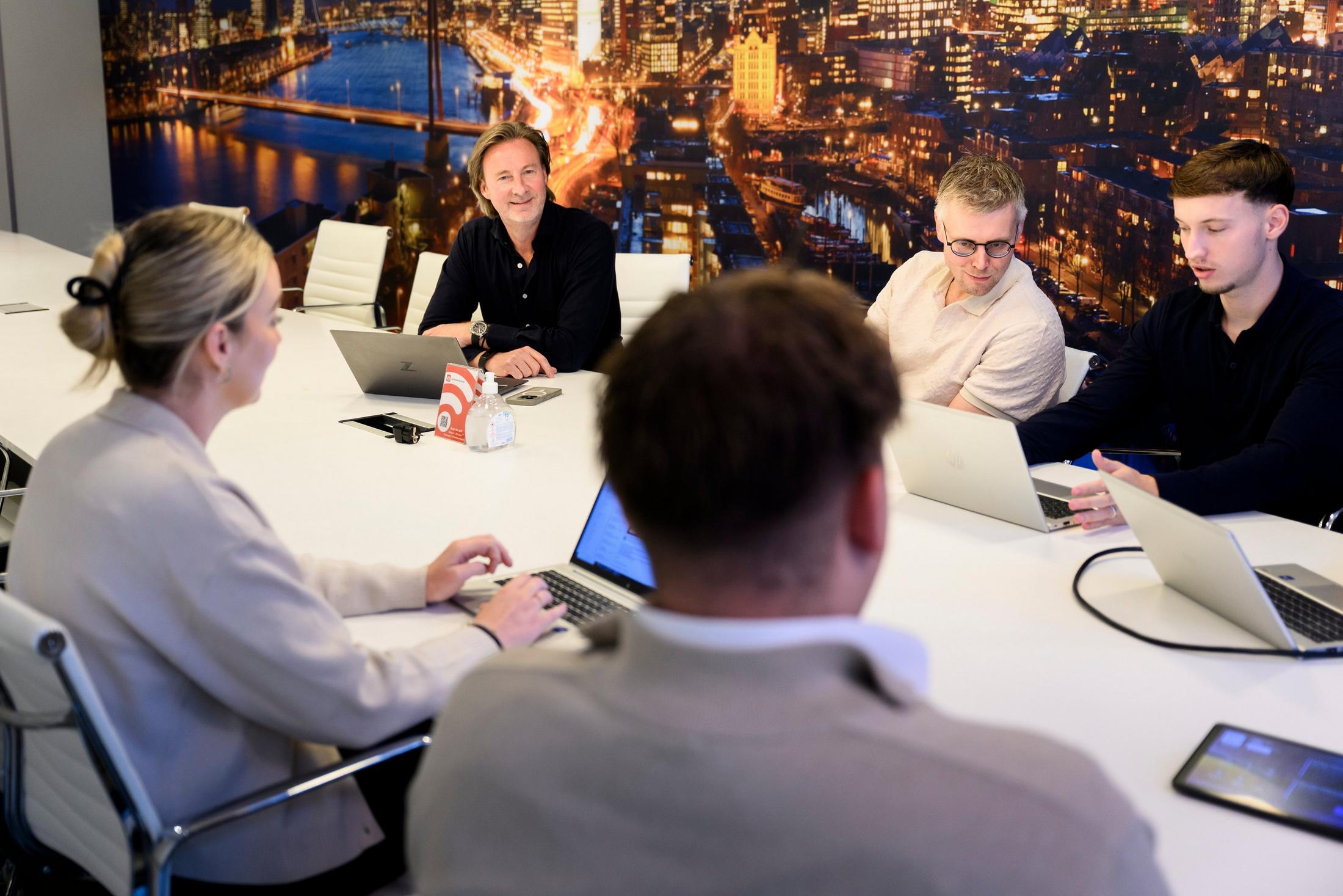 a group of people sitting at a table with laptops