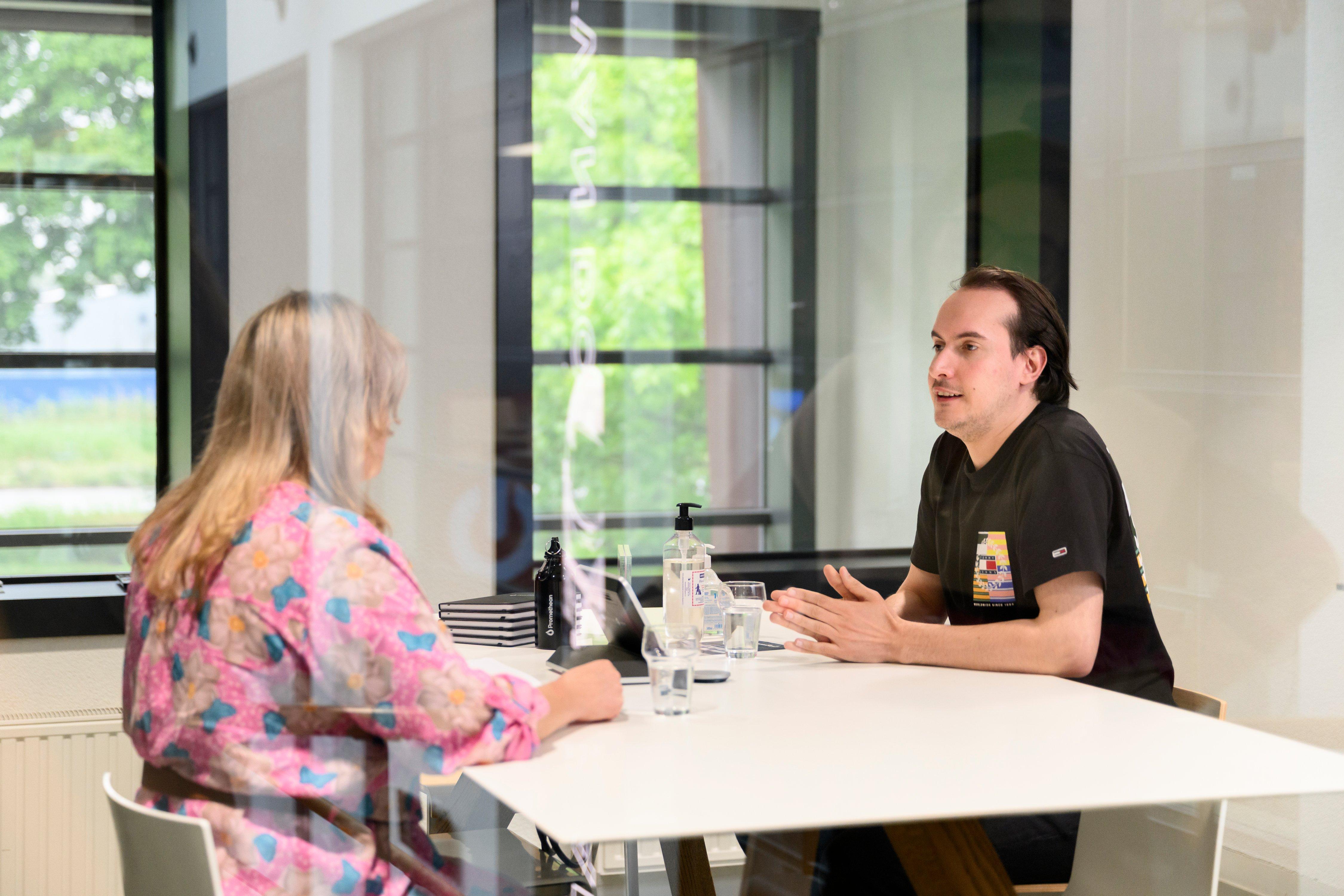a man and woman sitting at a table in a room with windows
