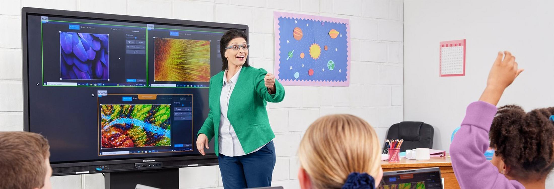 a woman standing in front of a large screen with a group of children