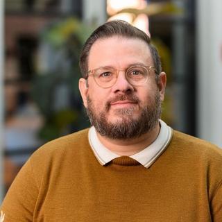a man with glasses and a beard sitting in a chair