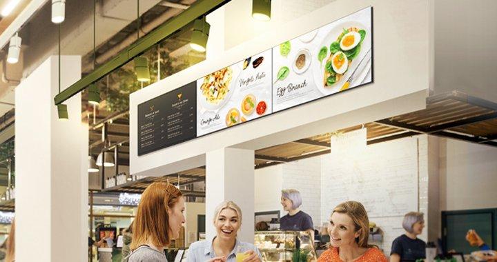 a group of people standing in a restaurant with a menu board