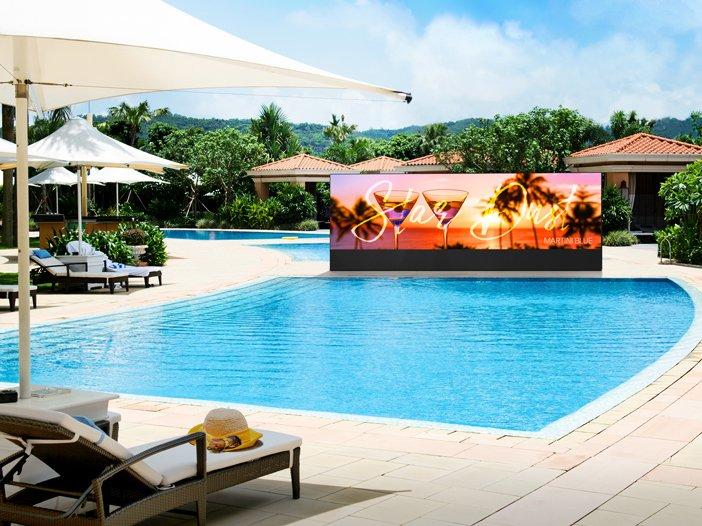 a pool with lounge chairs and umbrellas and a large screen