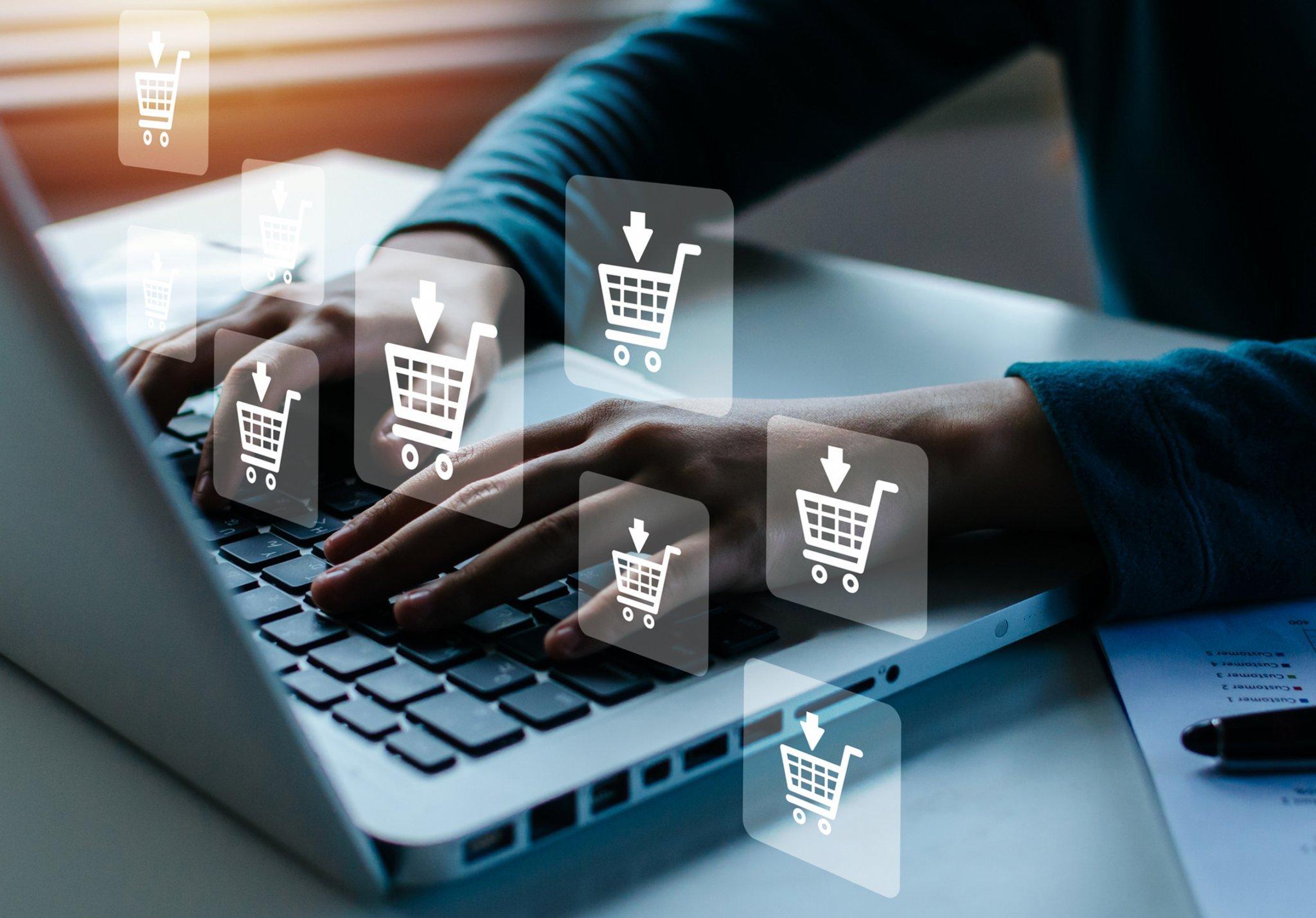 a person typing on a laptop with icons of shopping carts on the screen