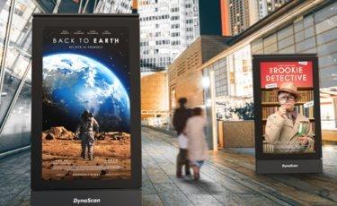 a group of people walking down a street with movie posters on the side