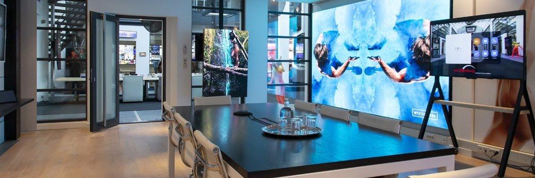 a room with a table and chairs and a large screen