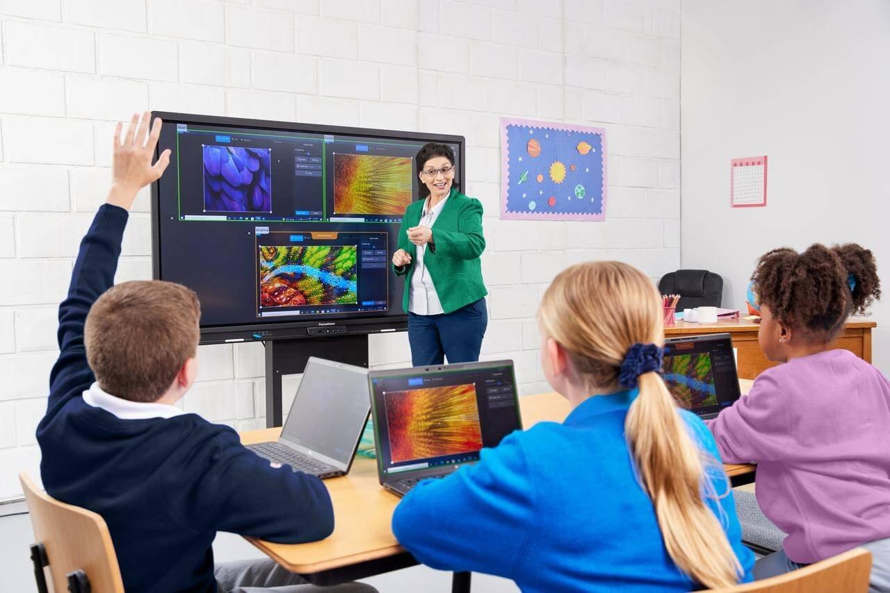 a group of children sitting at a table with laptops
