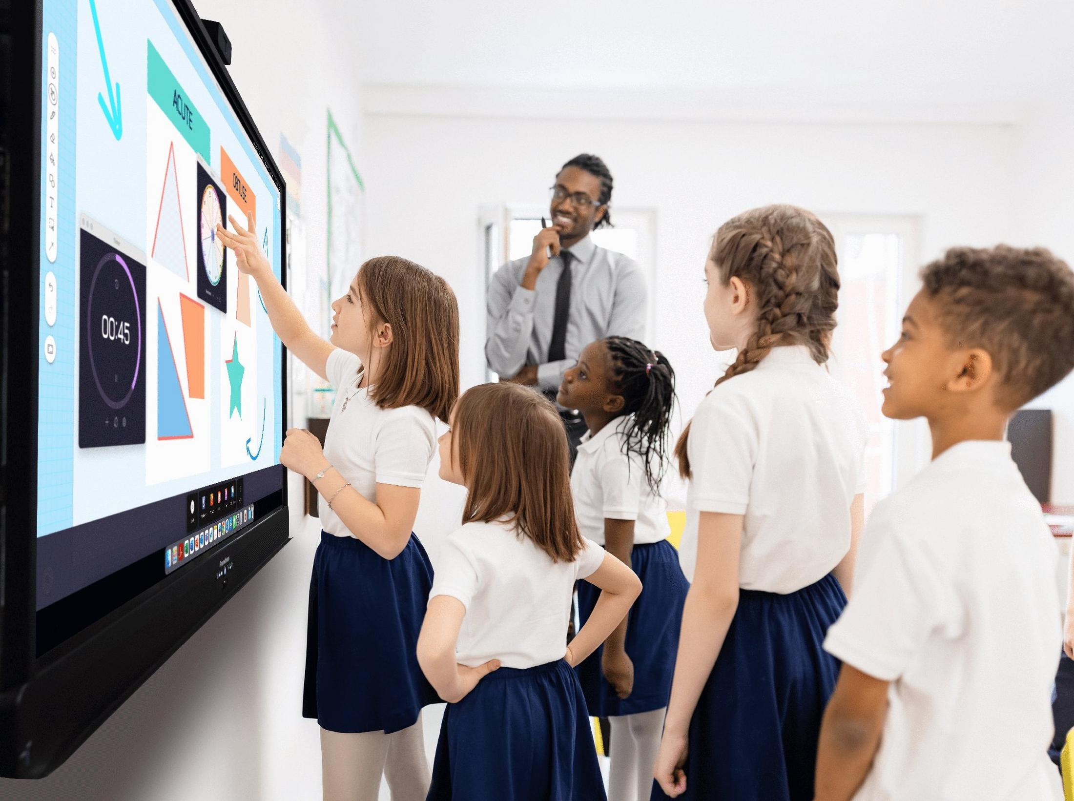 a group of children standing in front of a large screen