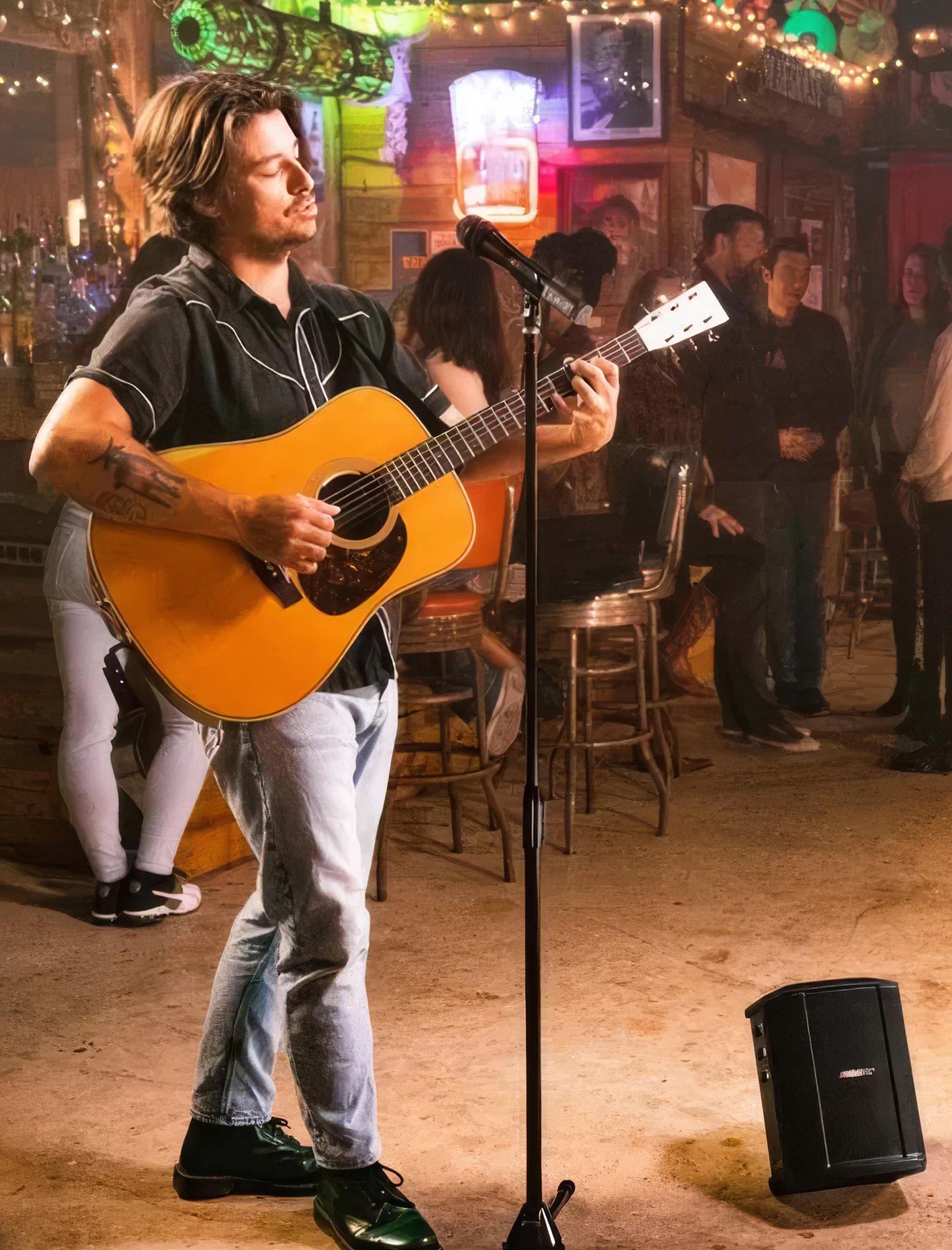 a man standing on a stage with a guitar and microphone