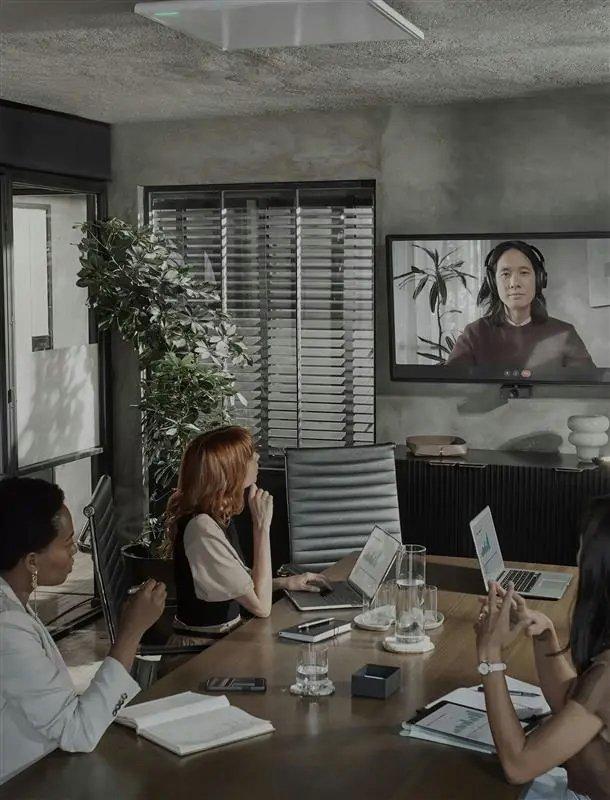 a group of people sitting around a table with laptops