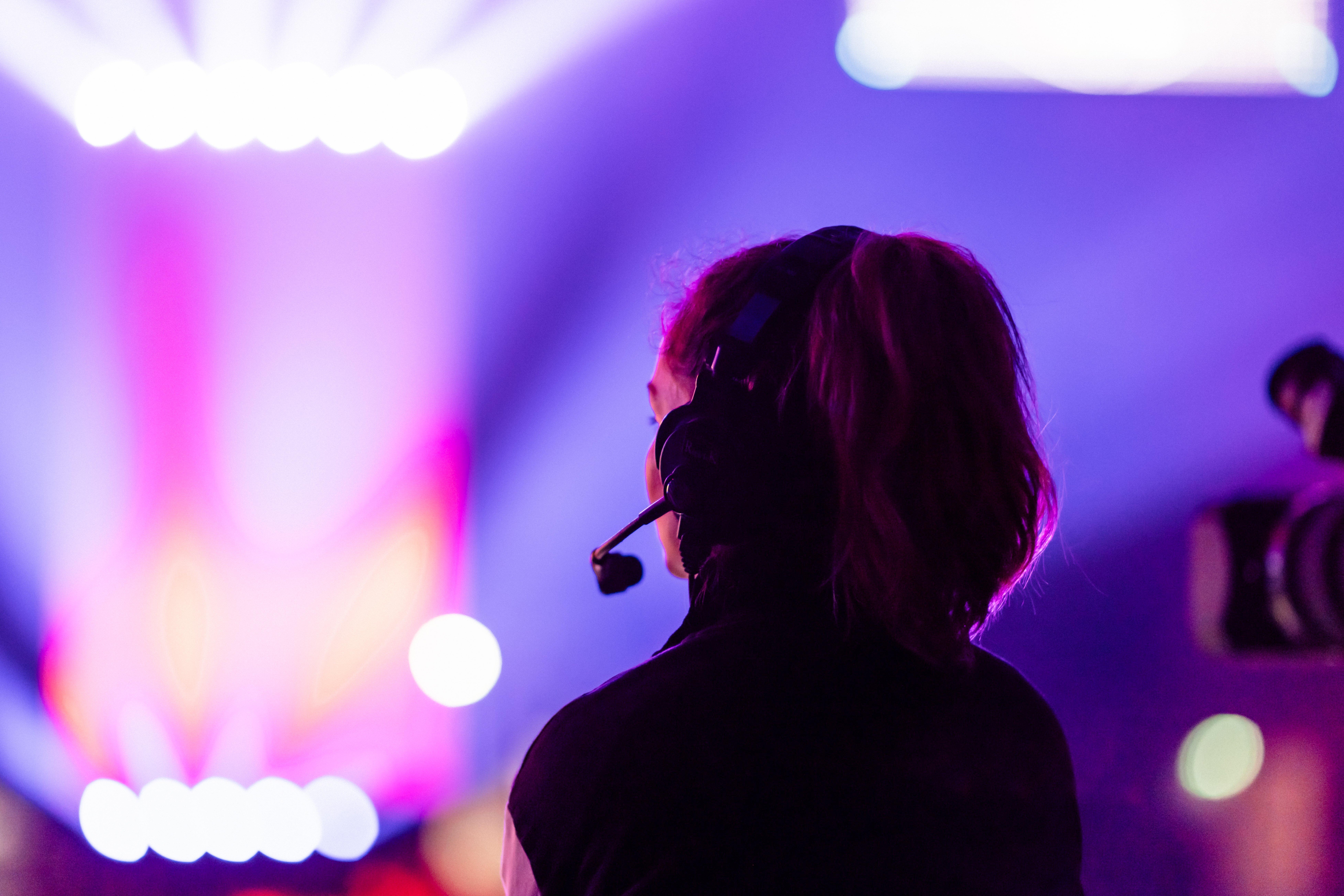 a woman wearing headphones and a headset is looking at a stage