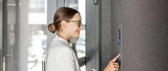 a woman in a white shirt and glasses is using a touch screen