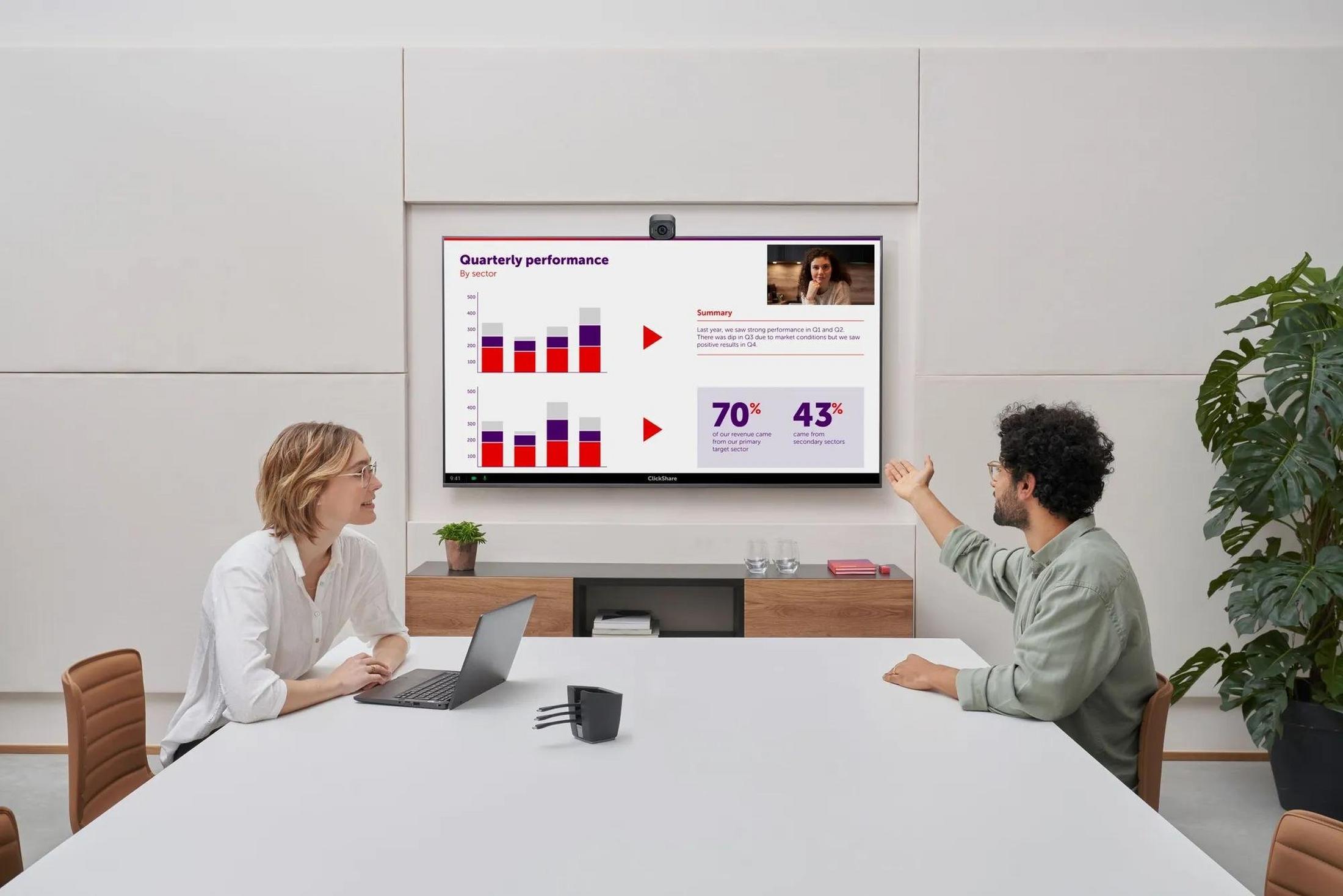 two people sitting at a table with a projector in the middle