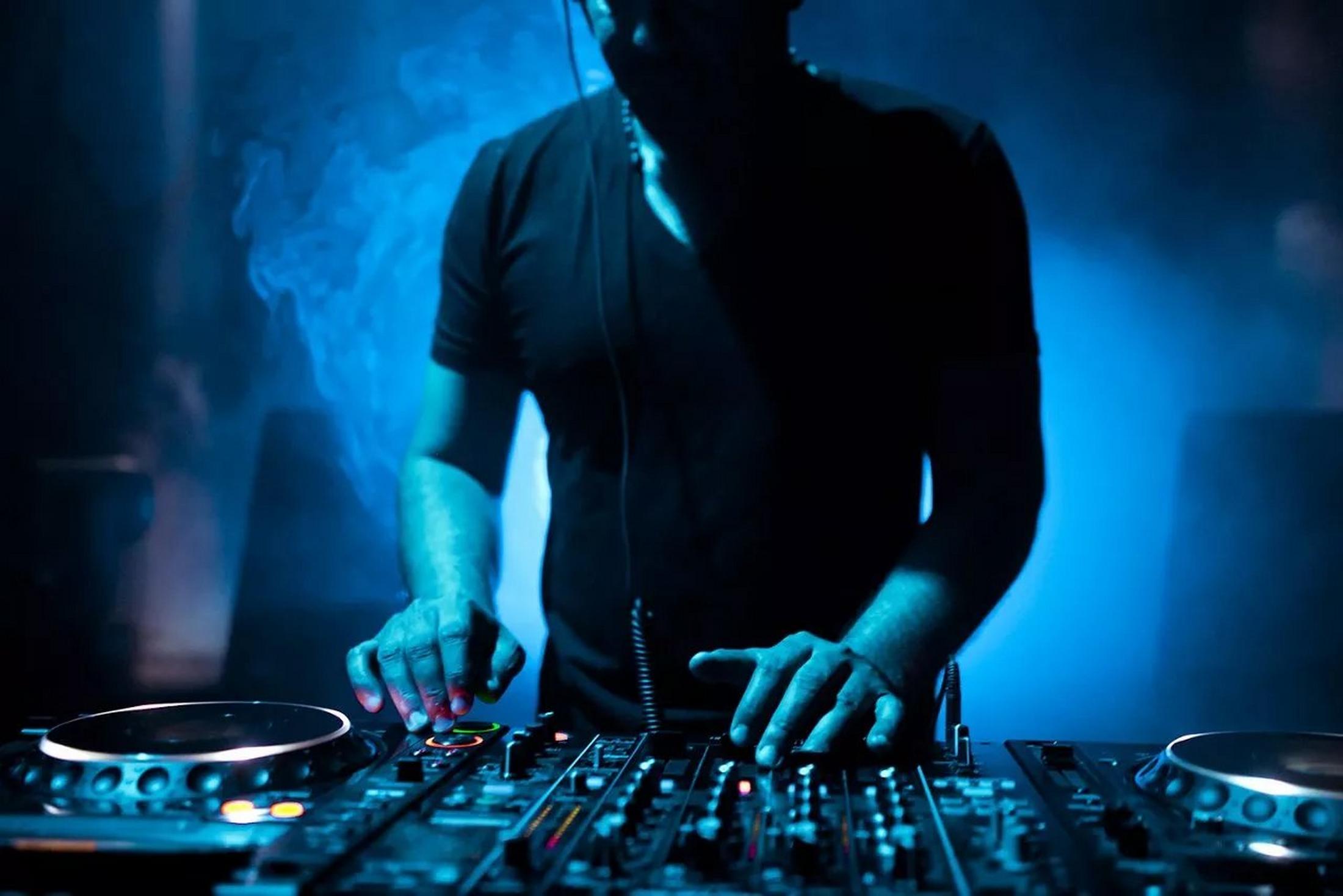 a dj mixing music in a dark room with smoke coming out of the speakers