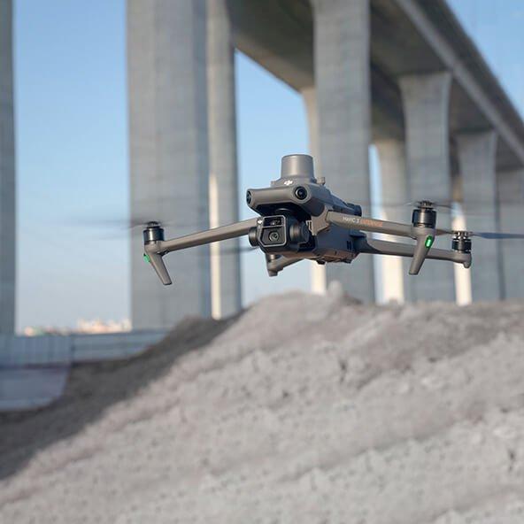 a drone flying over a bridge with a large pile of dirt