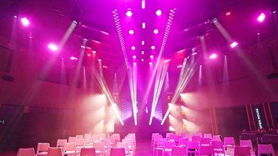 a large room with white chairs and purple lights