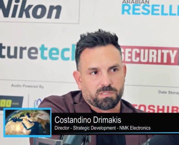 a man in a suit sitting at a table with a microphone