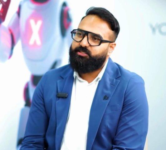 a man with a beard and glasses sitting in front of a robot