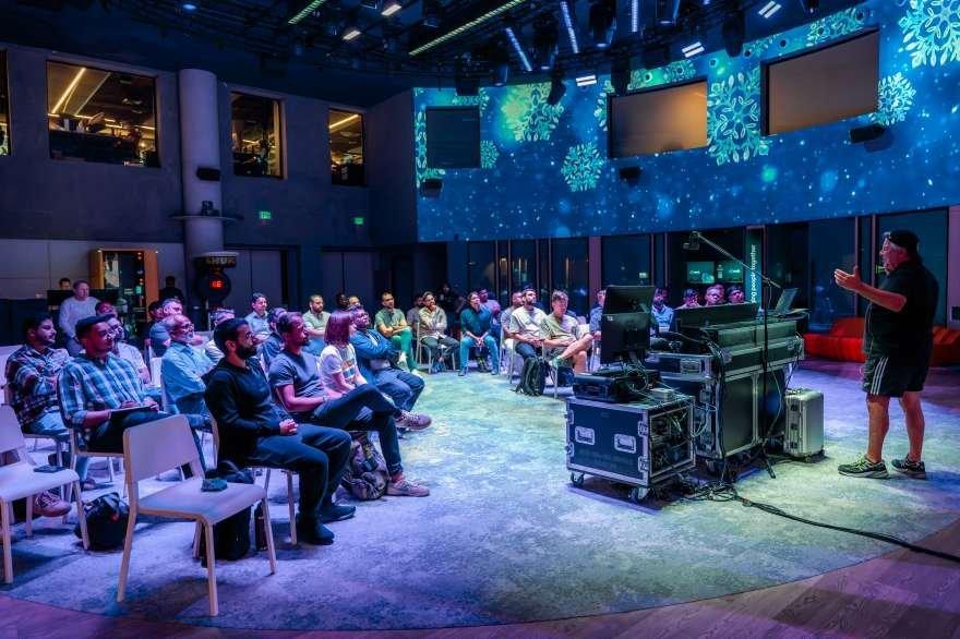 a man is speaking to a crowd of people in a room