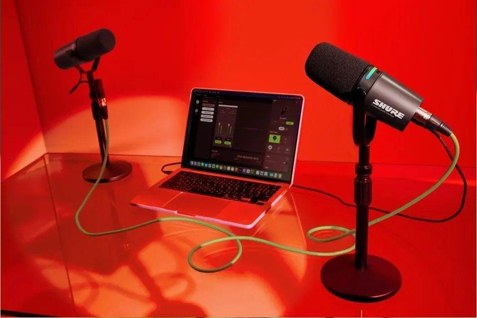 a laptop computer sitting on a red table with microphones