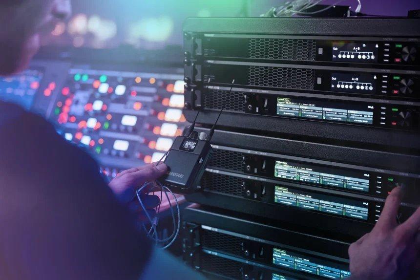 a man is holding a device in front of a rack of equipment